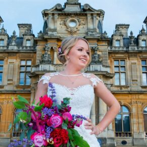 The smiling bride strikes a relaxed pose in front of Waddesdon Manor on her wedding day