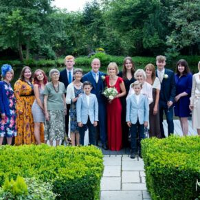 A relaxed group pose of the newlyweds with their family taken in the lovely gardens next to the lake at Saint Michael's Manor