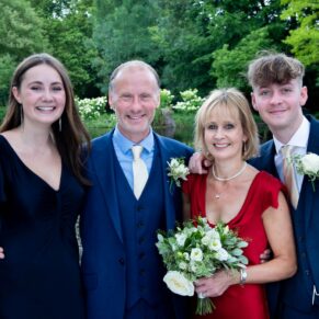 The bride and groom pose for a picture with their children in the colourful gardens of Saint Michael's Manor