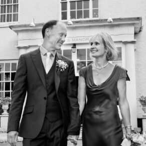 The smiling newlyweds take a stroll in front of their historic reception venue Saint Michael's Manor in St. Albans