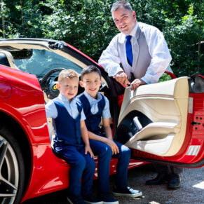 The smiling lads with their supercar in a lush green woodland setting