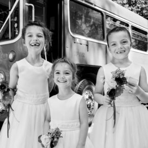 Giggling flower girls on route to the woodland civil ceremony pose outside their London bus