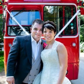Smiling bride and groom captured beside their red London bus in this wonderful woodland setting