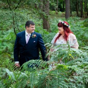 Natural woodland wedding portrait of the newlyweds captured walking through the ferns