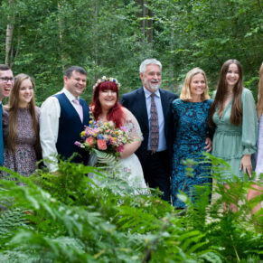A family group pose captured through the woodland ferns at this back to nature venue