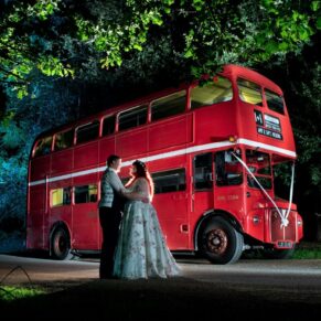 Dramatic floodlit shot of the newlyweds in front of their London bus captured at their GreenAcres Chiltern wedding