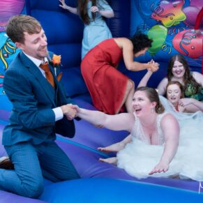 The groom rescues the bride from the bouncy castle at their Mercure Lambert Hotel wedding, Thame