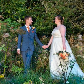 The bride and groom walk through a flower meadow at their Mercure Lambert Hotel wedding, Thame