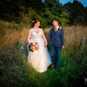 The newlyweds stroll through a meadow at their Mercure Lambert Hotel wedding, Thame