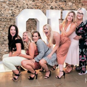 The bride's girlfriends enjoying the party atmosphere during the evening reception as they lark around by the giant LOVE letters