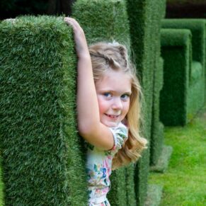 The flower girl posing besid the giant topiary love letters, captured at The Grange, Northwood wedding