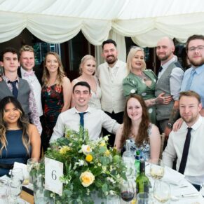 Group pose of some smiling friends in the marquee on a glorious summer's day