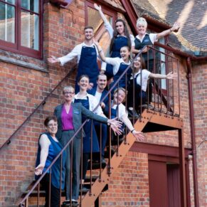 The staff pose on the steps of the Five Arrows Hotel for a fun image after an exhausting wedding day
