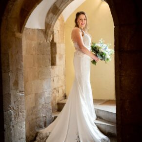 The bride captured through an arched stone doorway at her Farnham Castle wedding