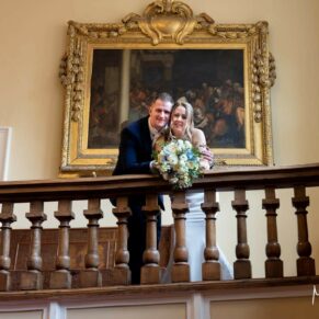 Photography classic pose of the bride and groom positioned on the grand staircase on their wedding day at Farnham Castle in Surrey