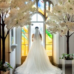 The back of the bride's dress captured in one of the many gorgeous stained glass windows at this Buckinghamshire venue