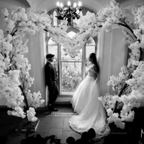 The newlyweds captured in one of the many gorgeous stained glass windows with a giant flower arch on their special day