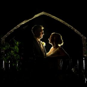 Whenever I bring out my floodlights on a wedding day, I know the magic is about to happen! Thankfully most wedding couples are really keen to see me capture some night shots on their wedding day. This is a really simple pose in a brick archway in the gardens of the Olde Bell Hotel in Hurley. A pose like this takes just a few moments, and some forward planning. The newlyweds in silhouette at night-time in a garden rose archway at their Olde Bell Hotel wedding reception in Hurley