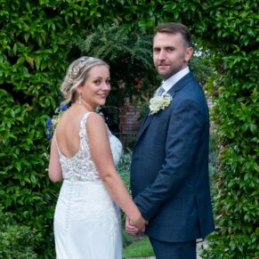The Olde Bell Hurley Wedding Photography - the newlyweds glance back at the camera in the hotel gardens