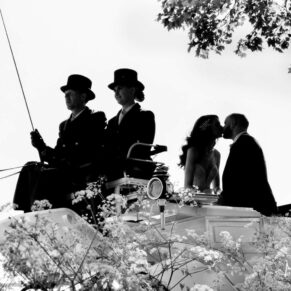 The newlyweds captured in a black and white silhouette pose with their horses and carriage through the flower borders at their Hedsor House wedding