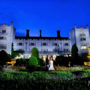 I'm a huge fan of taking dramatic wedding pictures at night-time - and backdrops like the one you see here at Danesfield House don't get any better - for this capture I'm beaming my floodlights to illuminate this entire vista - without my lighting tricks this photograph would be almost totally black apart from the dusky sky and the internal window lights Atmospheric floodlighting has been used to illuminate the entire building for this dramatic pose with the newlyweds at their winter wedding at Danesfield House Hotel