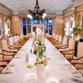 Dramatic angle of the long banqueting table all set up for the wedding breakfast in the restaurant at Danesfield House Hotel