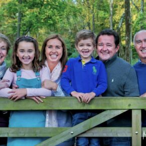 Natural family pose with family leaning against a gate captured in a woodland setting in the Chilterns