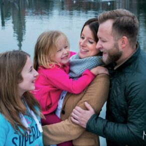 Family portrait captured by the River Thames in Marlow as the group giggle together with the river behind them