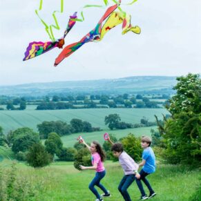 Kids portraits photography session capturing them flying a kite in the Buckinghamshire countryside on a windy day