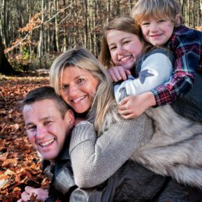 Family portrait group pose with everyone joining in with the hug in this colourful autumnal woodland scene