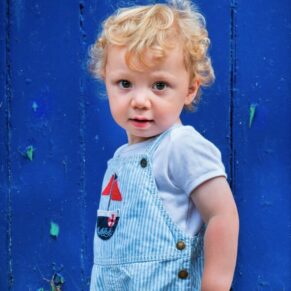 Colourful outdoor child portrait captured against a blue door in the Buckinghamshire area - making a pose as natural as vibrant as possible always gets great results