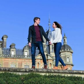 Walking couple portrait taken at Waddesdon Manor under perfect blue skies