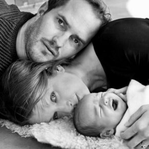 Parents and their baby laying on the ground for a dramatic black and white photography pose for their Buckinghamshire family portraits photo-shoot