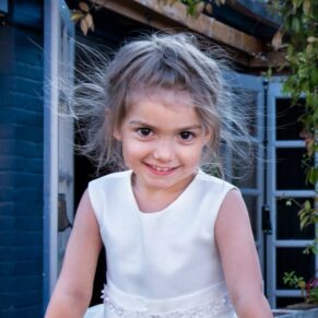 Buckinghamshire portrait photography of a gorgeous young smiling girl resting against a wall with sunlight streaming through her hair