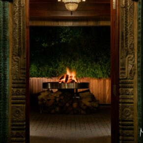 The view through the feature doorway after dark at this wedding reveals a stunning open firepit at The Crazy Bear Hotel in Stadhampton