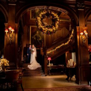 I'm always looking for a bit of atmosphere in my pictures, and the directional lighting I've used for this pose on the dramatic Christmassy staircase really ticks my box! There is minimal light inside Cliveden House on an overcast winter's day, so to achieve the results you see here requires a little bit of creativity. As for the finished result, I'm really thrilled with the final capture, as were the couple. There's just so much happening in this photograph, yet our eyes are drawn to the happy couple! Cliveden House interior of the Great Hall at Christmas with the newlyweds positioned on the staircase during their wedding reception