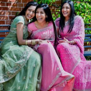 Buckinghamshire Asian Wedding Photography of three bridesmaids giggling whilst sat on a bench at The Dairy on the Waddesdon Estate