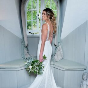 The bride stands in a feature window to showcase her gown in the period cottage on the estate