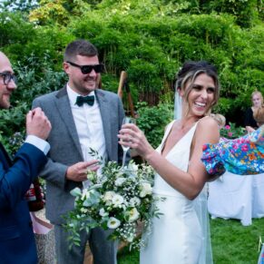 Candid shot of the couple with some of their giggling guests captured during their garden drinks reception