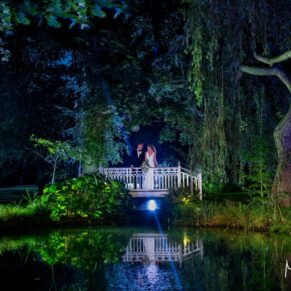 The newlyweds on the bridge at night-time with a little help from some floodlighting to create the absolute wow factor in this woodland setting