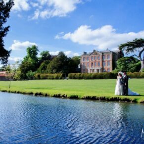 The newlyweds and their reflections captured across the water with the main house off on the horizon
