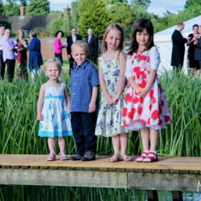 These adorable four children were captured on the wooden bridge going over the lake at this summer wedding