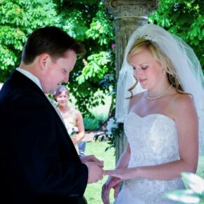 Ardington House Wedding Photographer - exchange of rings between the bride and groom during their outdoor ceremony