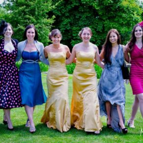 The giggling ladies walking towards the camera across the lawns with the stunning gardens behind them