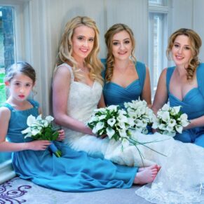 The bride and bridesmaids take a seat on the ground for a casual pose indoors at this lovely relaxed wedding