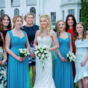 The bridal party pose for the camera in front of the Beaumont Estate White House at this informal summer wedding