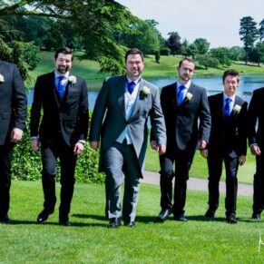 The groom and some male friends take a stroll through the grounds with the lake in the distance