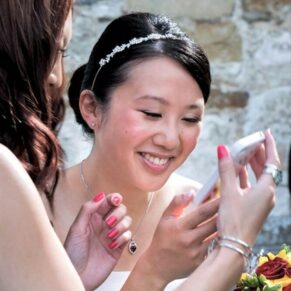 Candid and reportage Buckinghamshire wedding photographer - the bride giggles when she's shown a picture on a friend's phone