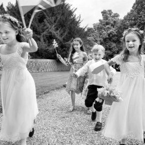 Wedding kids energetically running through the gardens at Chenies Manor