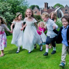 Some giggling wedding kids captured dashing through the colourful gardens in this glorious garden setting of Chenies Manor